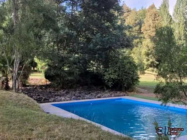 Cabaña pequeña vista desde jardín con árboles y pasto verde